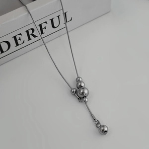 Macro-opname van zilveren roestvrijstalen Y-vormige ketting met ronde bolhangers en slang