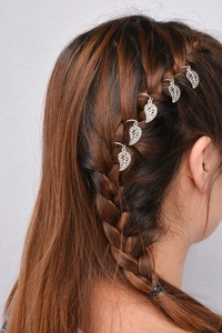 Detailed view of silver alloy leaf charms attached to braided hair with metal rings