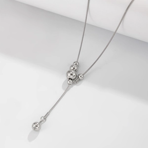 Detailweergave van zilveren Y-vormige slangenketting met gepolijste metalen kralen