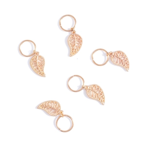 Close-up of five golden hollow leaf hair rings with detailed vein textures on white background