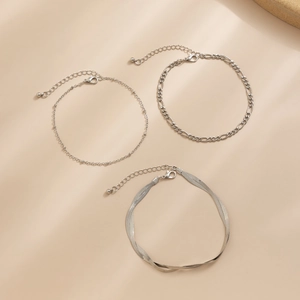 Dettaglio di un set di tre cavigliere color argento con catene Figaro e serpente