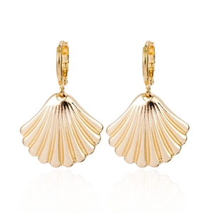 Détail de boucles d'oreilles coquillage doré avec texture polie et fermoir créole sécurisé