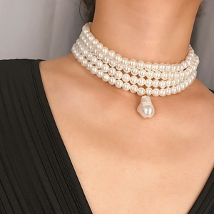 Detailopname van de drielaagse parelketting met een grote barokke parelhanger eraan