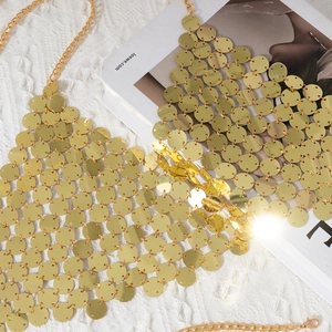 Detail of golden sequin body chain with metal rings on soft white faux fur background