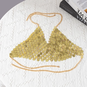 Close-up of golden sequins body chain with round metallic disks on white texture