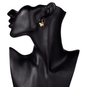 Detail of golden butterfly pendant earring on a black display model with huggie hoop