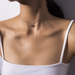 Close-up of minimalist silver butterfly pendant necklace worn on female neck
