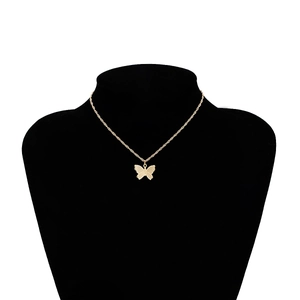 Macro detail of gold butterfly pendant with textured finish on thin cable chain