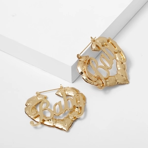 Detailansicht goldener Herzohrringe mit Baby-Schriftzug und feiner Bambustextur