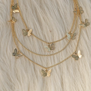 Three-layer gold butterfly chain necklace with detailed metal engraving on plush background