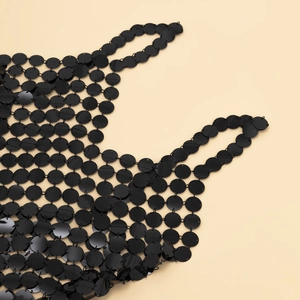 Gros plan de sequins noirs ronds et maillons métalliques sur une chaîne de corps sexy