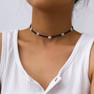 Primer plano del collar gargantilla hecho a mano con cuentas negras y pequeñas flores blancas