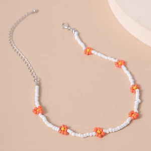 Detalle de collar de cuentas con margaritas naranjas y cierre de mosquetón de plata con cadena