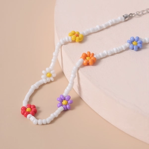 Detalle del collar de cuentas de margaritas de colores en soporte rosa con cadena de extensión