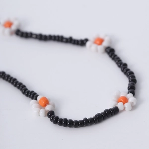 Detalle del collar de cuentas hecho a mano con cuentas negras y pequeñas flores de margaritas