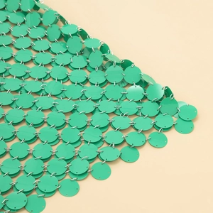 Détail de sequins verts et d'anneaux argentés sur une chaîne de corps géométrique