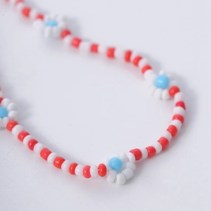 Vista de detalle del collar de cuentas hecho a mano en rojo y blanco con flores