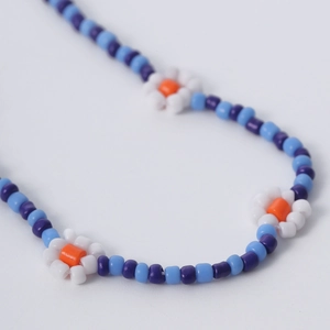 Primer plano de collar de cuentas coloridas con margaritas blancas hechas a mano y azul