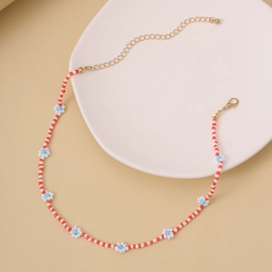 Primer plano de collar hecho a mano con cuentas rojas y detalles de margaritas blancas