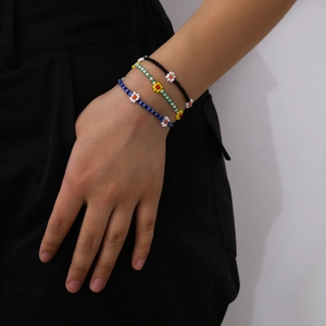 Detalle de tres pulseras de cuentas de colores con flores en la muñeca para estilo diario