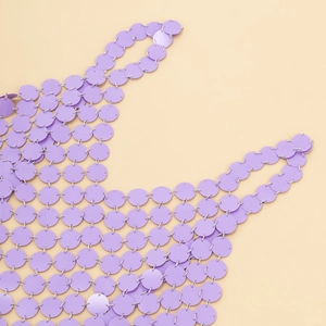 Gros plan de paillettes violettes et anneaux argentés formant un haut de corps mesh