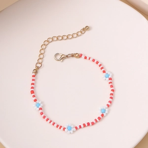 Detalle de pulsera de cuentas hecha a mano con flores de margarita y cuentas rojas