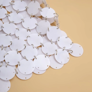 Détail macro de paillettes rondes blanches reliées par des anneaux métalliques argentés