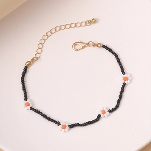 Detalle macro de pulsera de cuentas con flores y cierre de mosquetón en tono dorado
