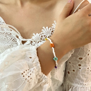 Detalle de un collar de cuentas de margarita hecho a mano sobre encaje blanco