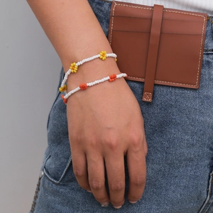 Detalle de pulseras artesanales de cuentas de margaritas en colores blanco, amarillo y naranja