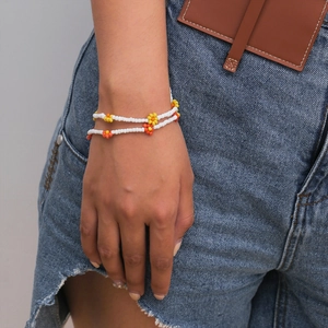 Detalle de pulseras de cuentas de margaritas de colores sobre tela vaquera y cuero