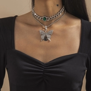 Details einer silbernen Cubankette mit Smaragd-Edelstein und Strass-Schmetterlingsanhänger