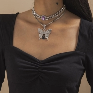 Detail einer silbernen Panzerkette mit lila Edelstein und Diamant-Schmetterlingsanhänger