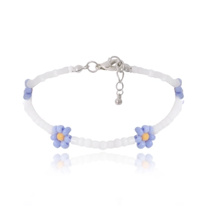 Detalle de collar de cuentas blancas con dijes de margaritas azules y cierre plateado