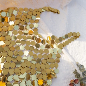 Dettaglio del top sexy a catena con paillettes dorate e dischi metallici rotondi