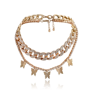 Detalle de collar de capas dorado con cadena cubana y colgantes de mariposa con brillo