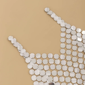 Dettaglio di paillettes metalliche argentate e catena del corpo geometrica scavata