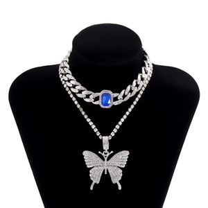 Nahaufnahme der zweilagigen Cubankette mit blauem Stein und Schmetterlingsanhänger am Model