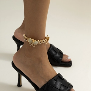 Golden Cuban link anklet with a full crystal butterfly pendant on a model's ankle