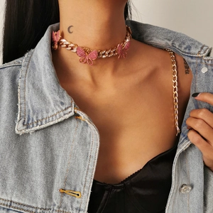 Golden Cuban chain choker with pink rhinestone butterfly charms worn by a model