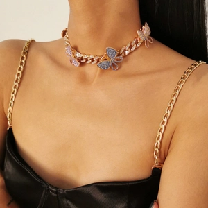 Close-up of golden Cuban chain necklace with three colorful rhinestone butterflies