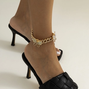 Close-up of gold chunky chain anklet with butterfly pendant and glittering rhinestones