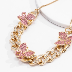 Detail of golden Cuban chain anklet featuring a butterfly pendant with pink and white crystals