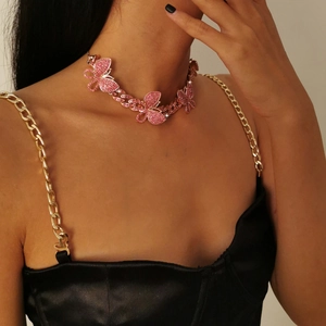 Close-up of cuban chain necklace with pink rhinestone butterfly pendants on a model