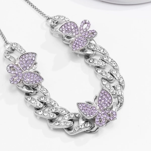 Detail of silver Cuban link anklet with crystal butterfly pendants in purple and pink