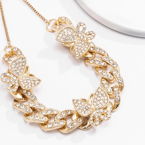 Close-up detail of golden butterfly Cuban chain with sparkling rhinestone pavé setting