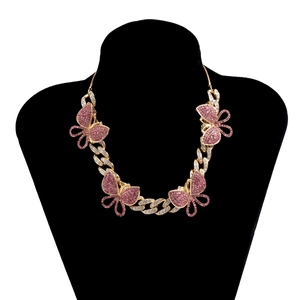 Close-up of golden cuban link necklace with pink crystal butterfly pendants on a bust