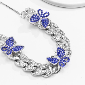 Detail of silver Cuban chain anklet featuring three butterflies with blue rhinestones