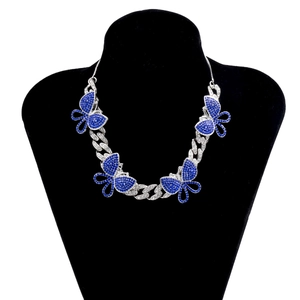 Detail of silver Cuban link necklace featuring sparkling blue rhinestone butterflies