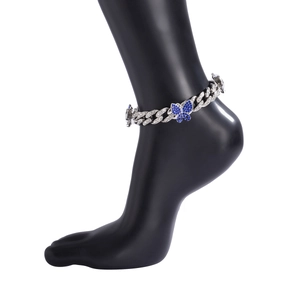 Close-up of iced out Cuban link anklet with blue rhinestone butterflies on a model